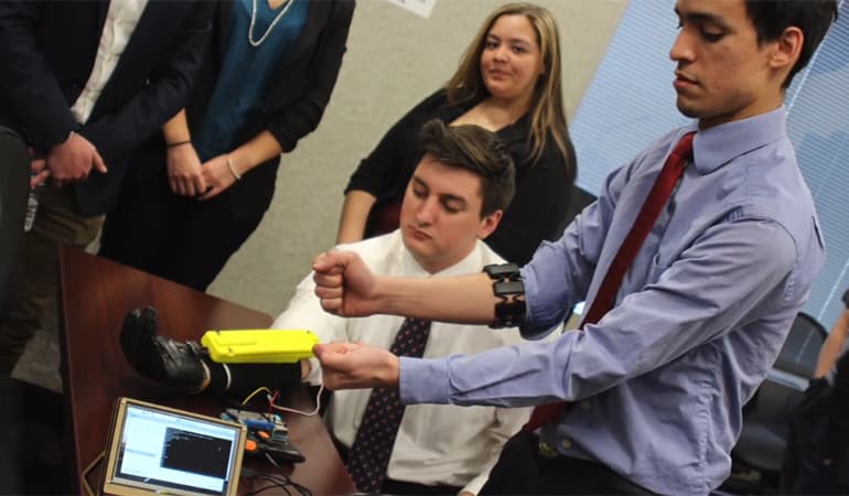 student showing client hand-gripping device he invented