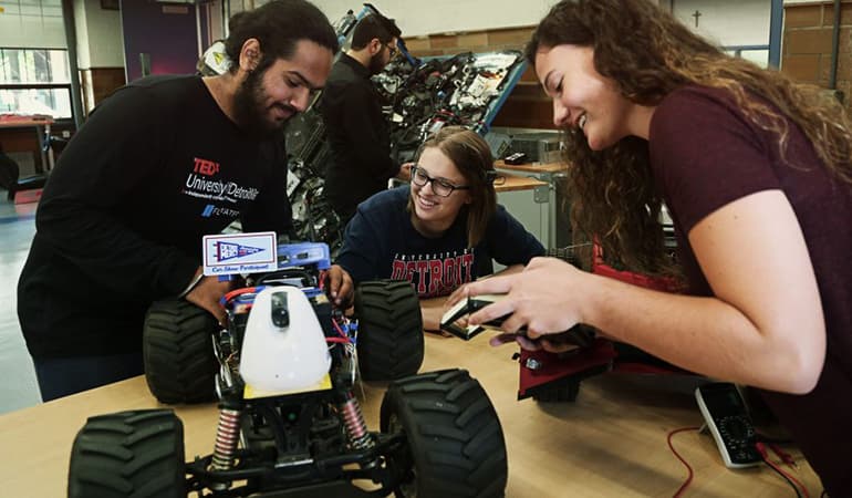 3 students around robot device and computer