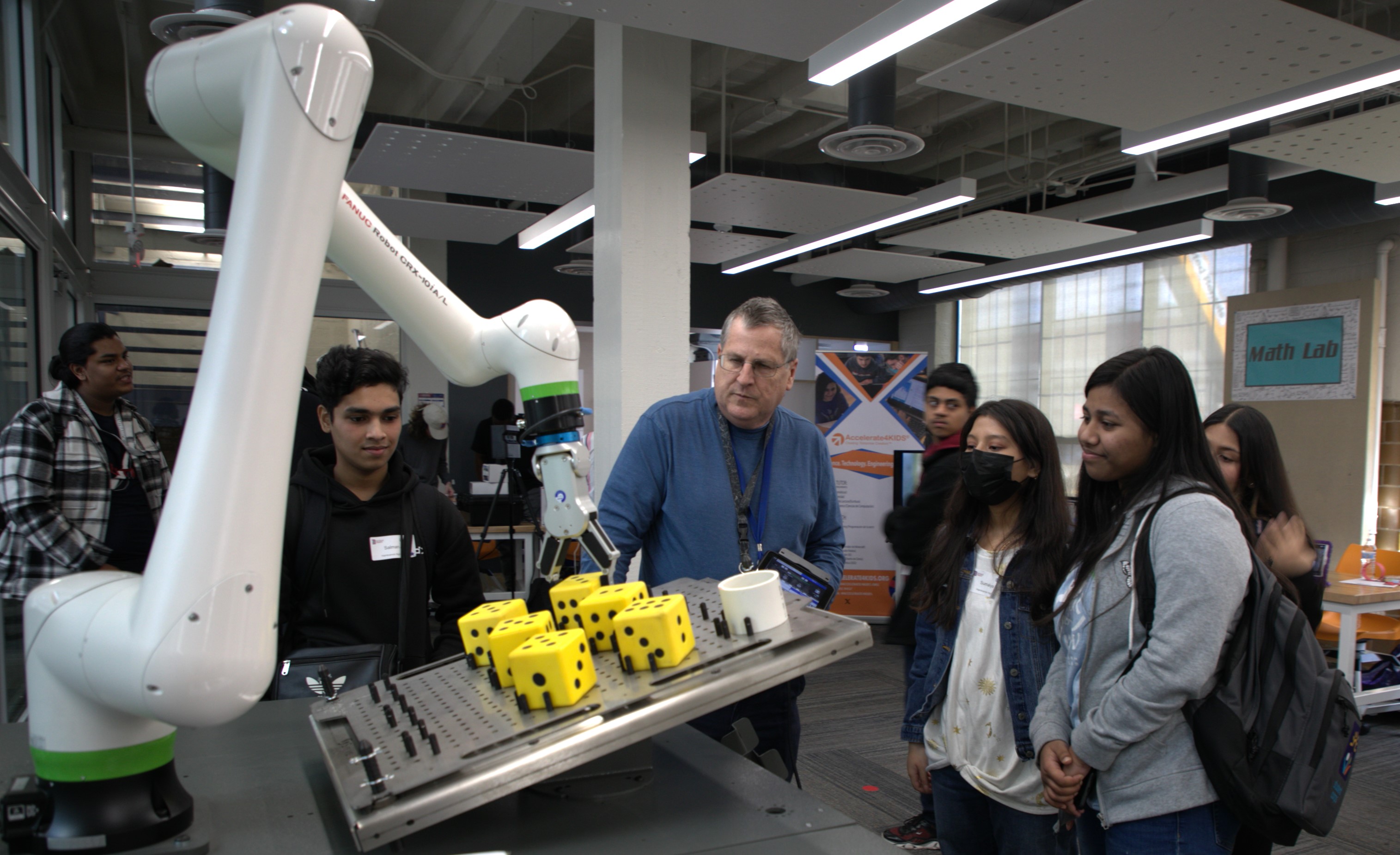 Professor showing high school students how to operate a robotic arm
