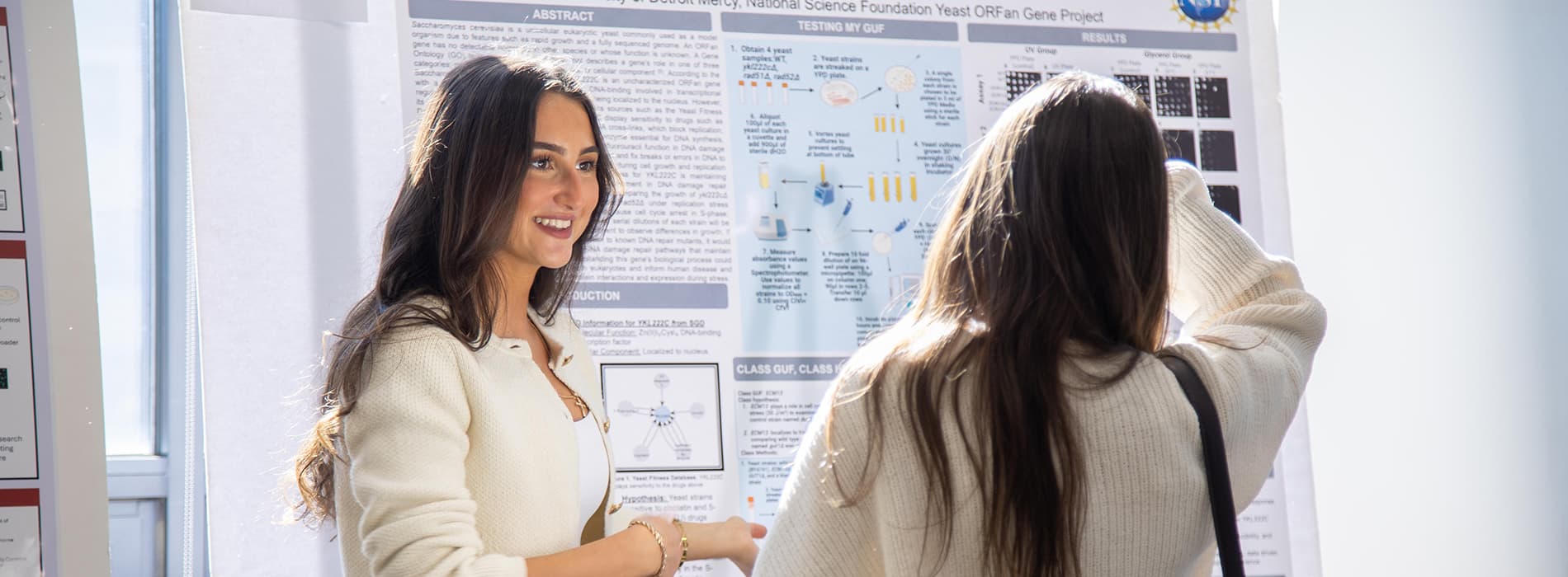 female student discussing poster information at research symposium
