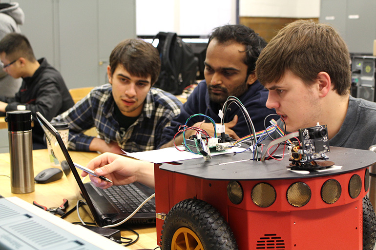 3 male students by a robot car