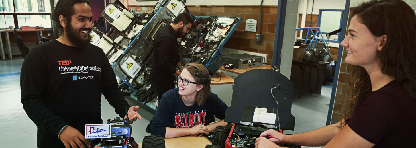 two students, one male one female, working on an engine-looking project