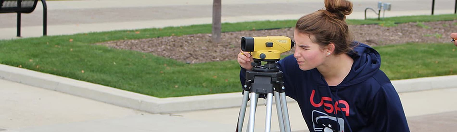 female student using and optical survey device.