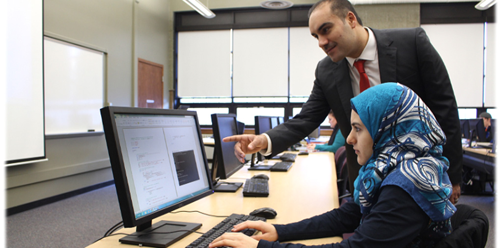 Female computer science student at computer with professor