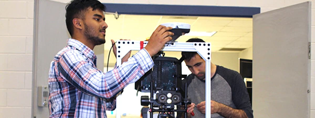 two Detroit Mercy working on robot for competition