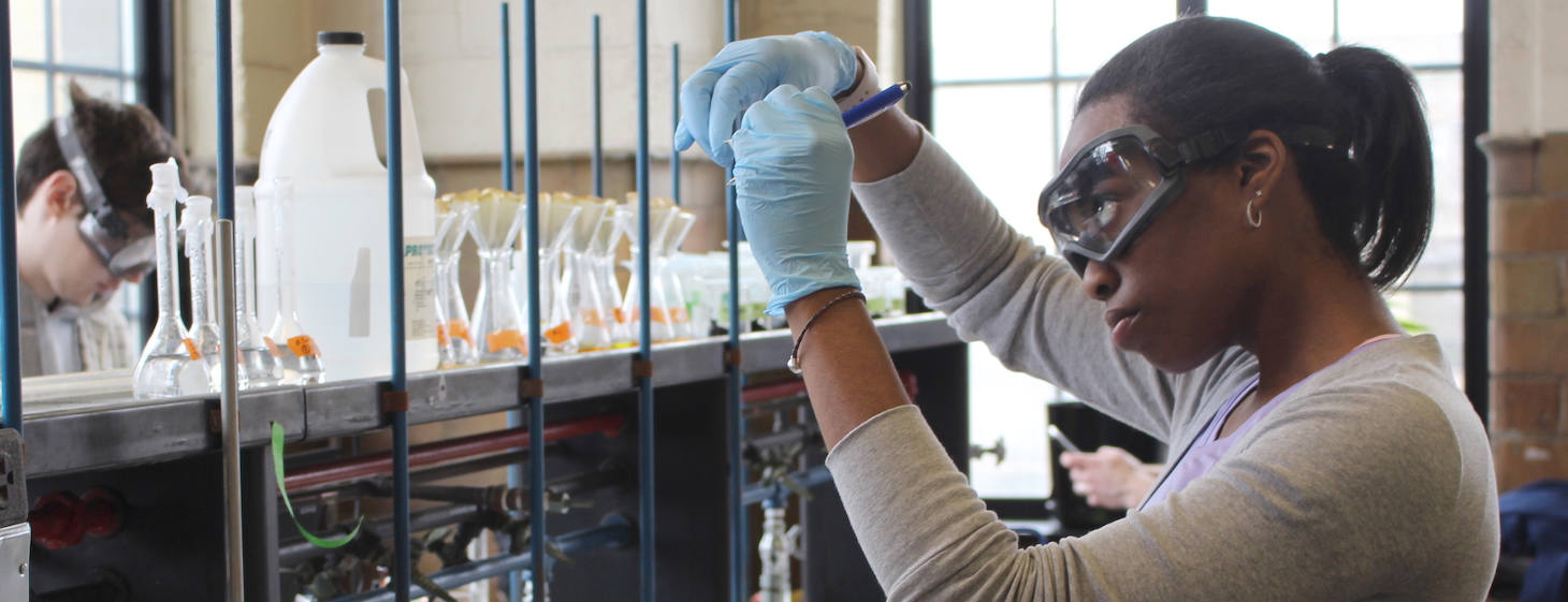 Student in chemistry lab holding up and labeling a sample.