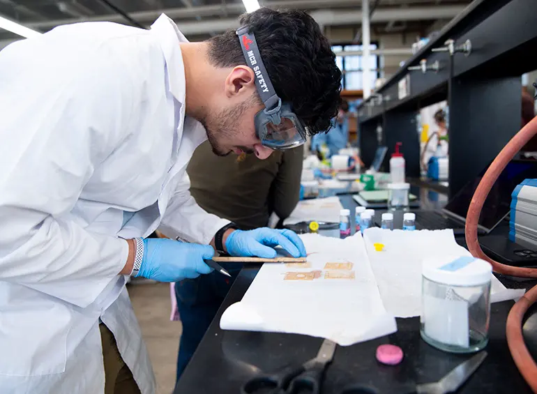 male student in chem glasses doing lab work
