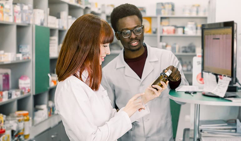 pharmacy student with pharmacist looking at a bottle description