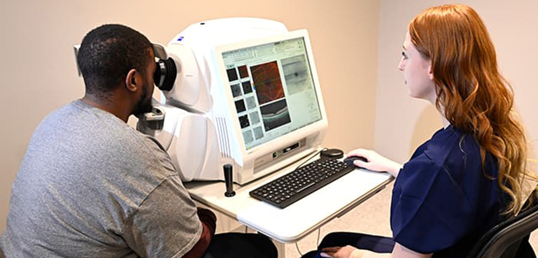 student working with patient on angioplex machine