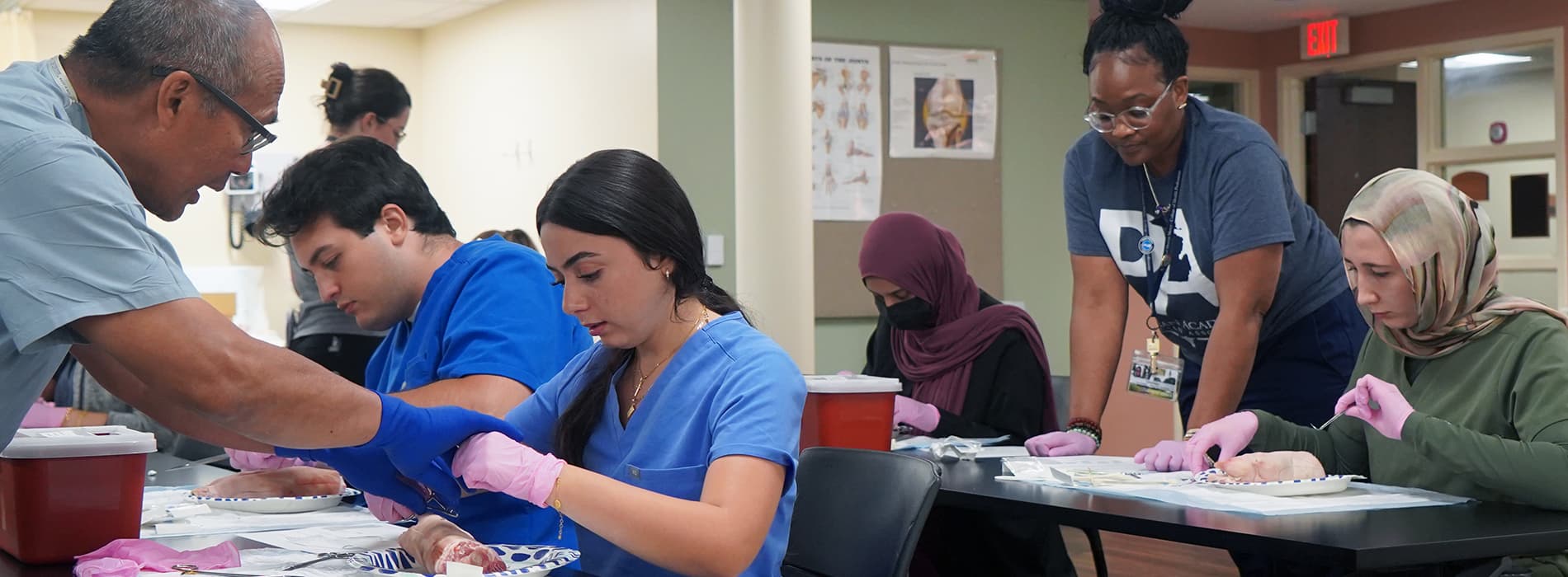 PA students suturing at desks with instructors