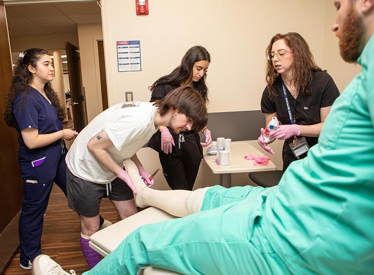 Male PA student practice casting over male patient foot