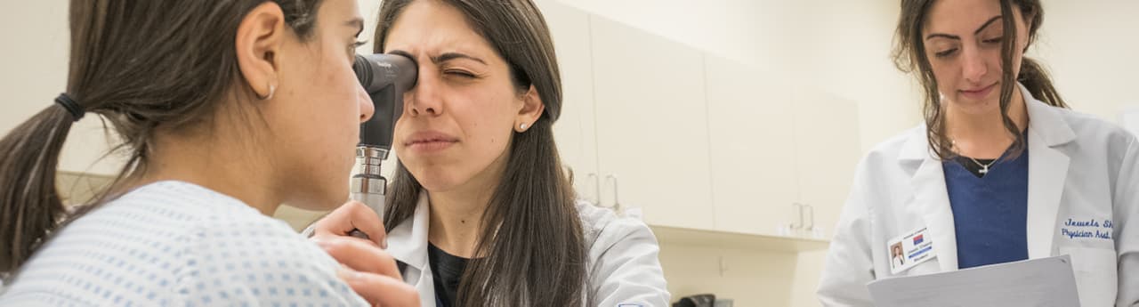 student pre-health student using otoscope to look in patient ear supervised by a prof