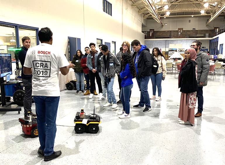 high school students around a vehicle robot
