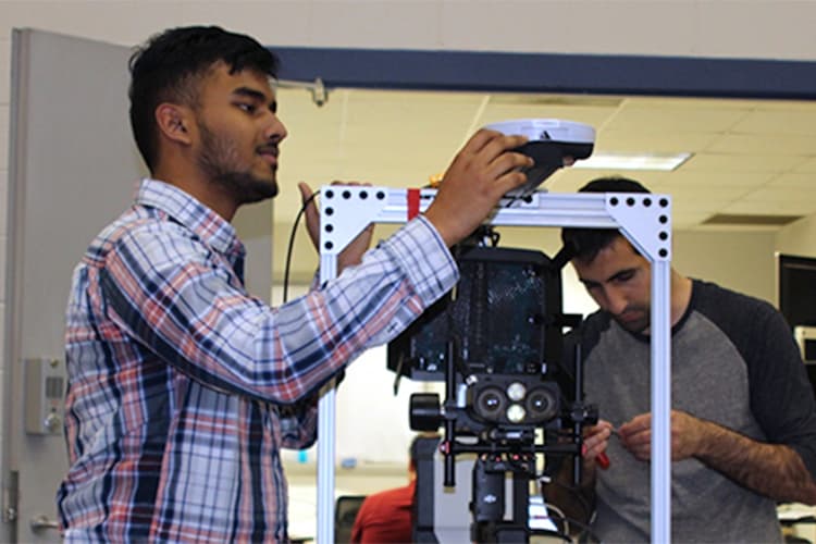 two students reviewing a robotic machine